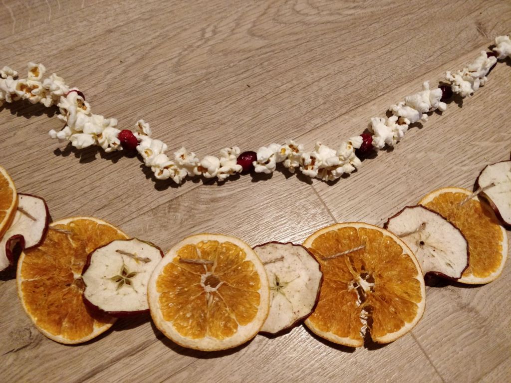 one row of popcorn and cranberry garland above an alternately threaded dried disks of orange and apple garland.